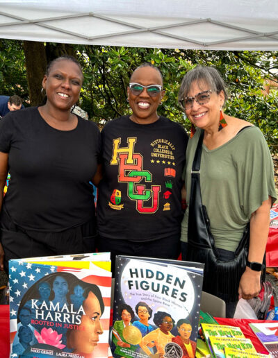 Three African American smiling in front of children's book at the festival.