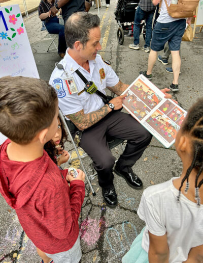 An EMT reading a children’s book to a couple of young children.